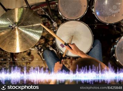 music, people, musical instruments and technology concept - close up of musician with drumsticks playing drum kit at concert at sound recording studio. drummer playing drum kit at sound recording studio