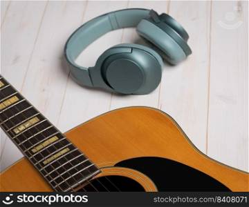 Music recording scene with guitar, empty music sheet, pencil and headphones on white wooden table