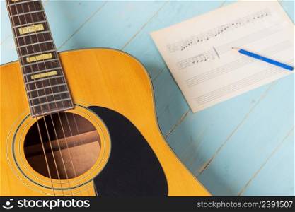 Music recording scene with guitar, music sheet and pencil on wooden table, closeup