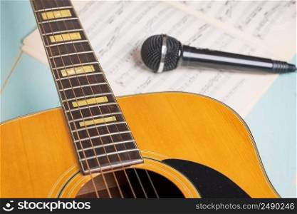 Music recording scene with guitar, music sheets and black microphone on wooden table