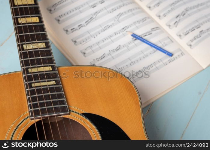 Music recording scene with guitar, music sheets and pencil on wooden table, closeup