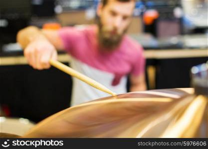 music, sale, people, musical instruments and entertainment concept - close up of male musician playing cymbals at music store