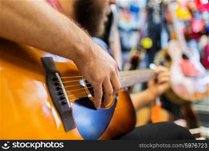 music, sale, people, musical instruments and entertainment concept - close up of man playing guitar at music store