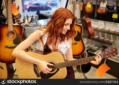 music, sale, people, musical instruments and entertainment concept - female musician or customer playing bass guitar at music store