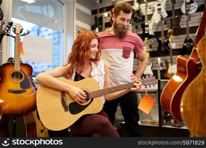 music, sale, people, musical instruments and entertainment concept - happy couple of musicians with guitar at music store