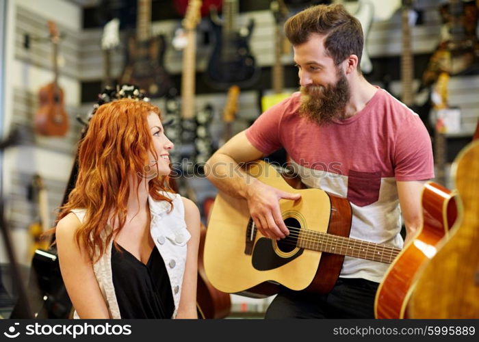 music, sale, people, musical instruments and entertainment concept - happy couple of musicians with guitar at music store