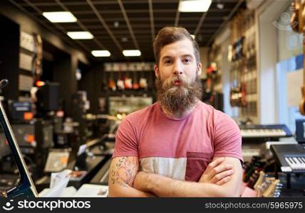 music, sale, people, musical instruments and entertainment concept - male assistant or customer with beard at music store