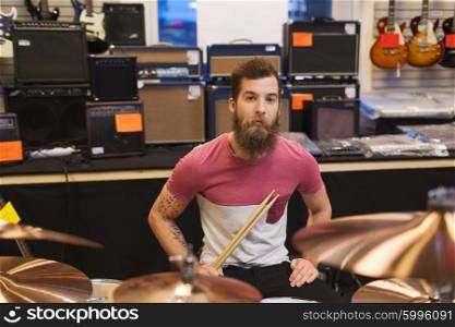 music, sale, people, musical instruments and entertainment concept - male musician at drum kit cymbals in music store