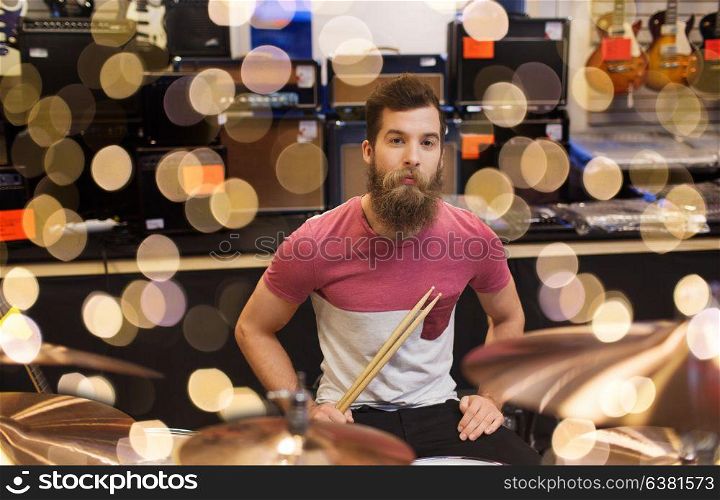 music, sale, people, musical instruments and entertainment concept - male musician at drum kit cymbals in music store. male musician with cymbals at music store