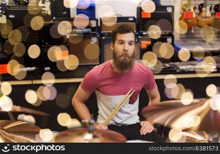 music, sale, people, musical instruments and entertainment concept - male musician at drum kit cymbals in music store. male musician with cymbals at music store