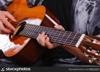 Music, sound, passion concept. Man playing on acoustic guitar, studio shot, black background.. Closeup of man playing acoustic guitar