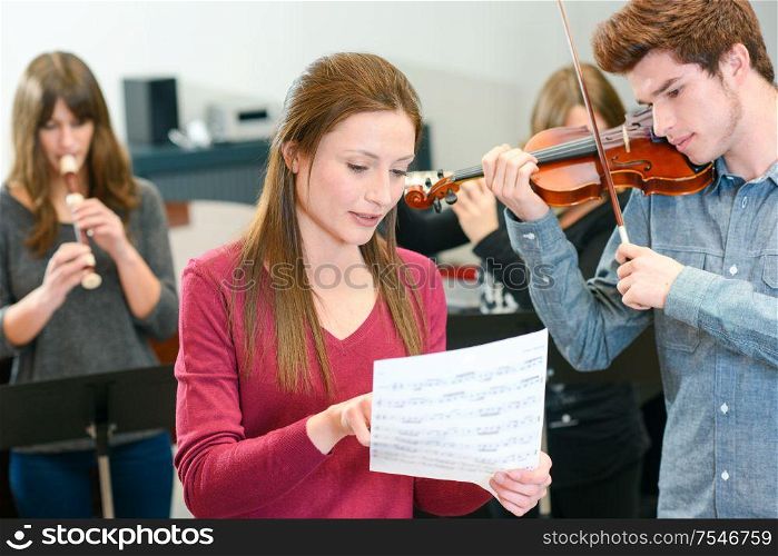 music teacher tutoring young man to play violin