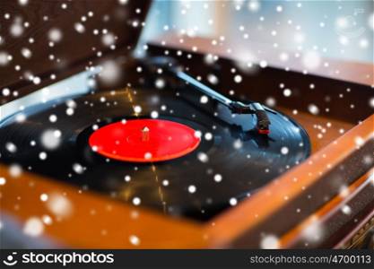 music, technology and object concept - close up of vintage record player with vinyl disc over snow