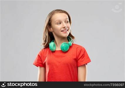 music, technology and people concept - happy teenage girl in headphones and red t-shirt over grey background. happy teenage girl with headphones