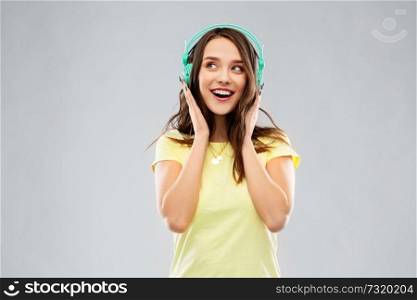 music, technology and people concept - happy young woman or teenage girl with headphones over grey background. happy young woman or teenage girl with headphones