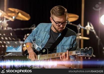 music, technology and people concept - male guitarist playing electric guitar at sound recording studio. guitarist playing guitar at sound recording studio