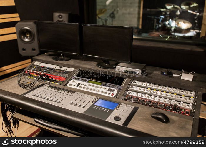 music, technology, electronics and equipment concept - mixing console and computer monitors at sound recording studio