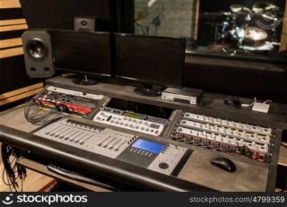 music, technology, electronics and equipment concept - mixing console and computer monitors at sound recording studio