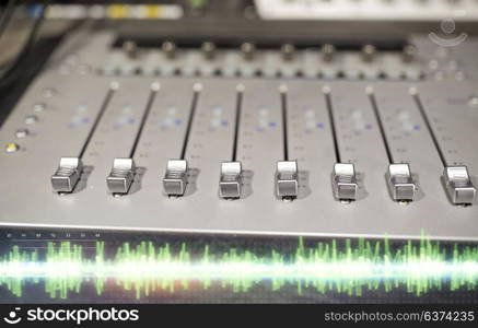 music, technology, electronics and equipment concept - mixing console at sound recording studio. music mixing console at sound recording studio