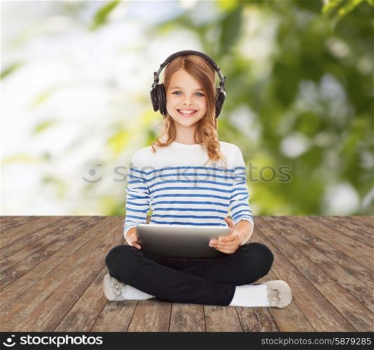 music, technology, people and childhood concept - happy girl with headphones and tablet pc computer over greed background
