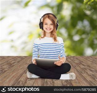 music, technology, people and childhood concept - happy girl with headphones and tablet pc computer over greed background