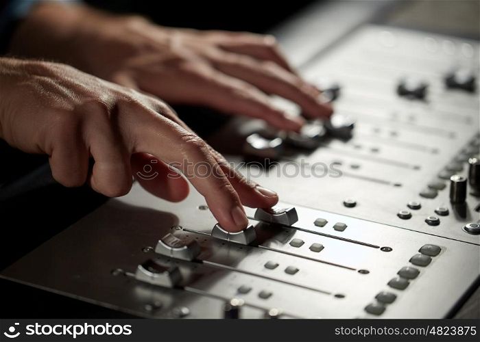 music, technology, people and equipment concept - hands using mixing console in sound recording studio