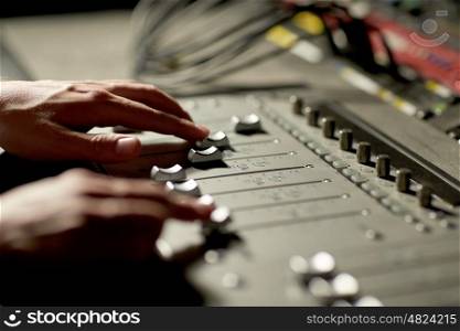 music, technology, people and equipment concept - hands using mixing console in sound recording studio