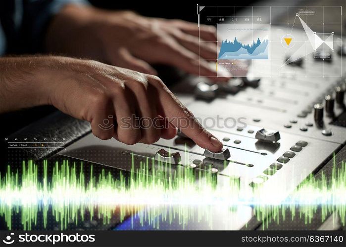 music, technology, people and equipment concept - hands using mixing console in sound recording studio. hands on mixing console in music recording studio