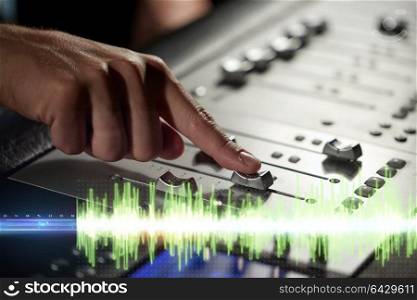 music, technology, people and equipment concept - hands using mixing console in sound recording studio. hands on mixing console in music recording studio