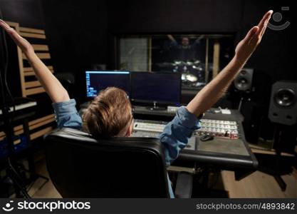 music, technology, people and equipment concept - happy man at mixing console in sound recording studio