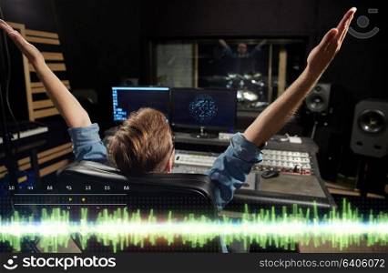music, technology, people and equipment concept - happy man at mixing console in sound recording studio. man at mixing console in music recording studio