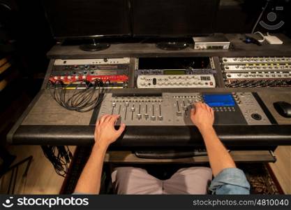 music, technology, people and equipment concept - man using mixing console in sound recording studio