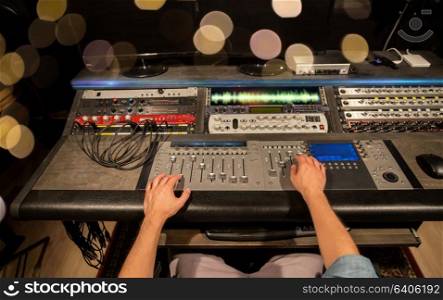 music, technology, people and equipment concept - man using mixing console in sound recording studio. man using mixing console in music recording studio