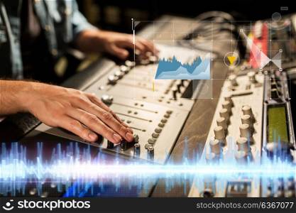 music, technology, people and equipment concept - sound engineer hands using mixing console at recording studio. hands on mixing console at sound recording studio