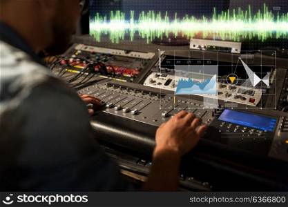 music, technology, people and equipment concept - sound engineer with mixing console recording track at studio. sound engineer at recording studio mixing console