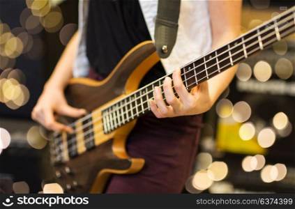 musical instruments, entertainment and people concept - close up of female musician playing guitar at music studio over lights background. close up of musician with guitar at music studio