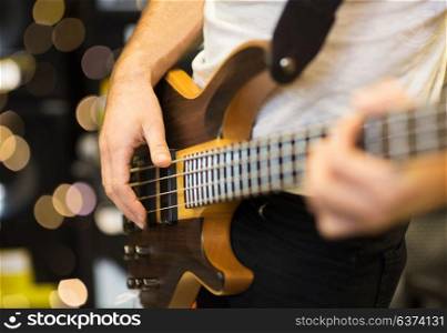 musical instruments, entertainment and people concept - close up of male musician playing guitar at music studio over lights background. close up of musician with guitar at music studio