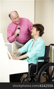 Musician in wheelchair playing the piano while her husband sings.