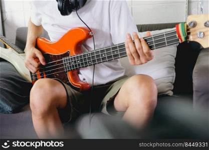 Musician playing bass guitar on sofa at home
