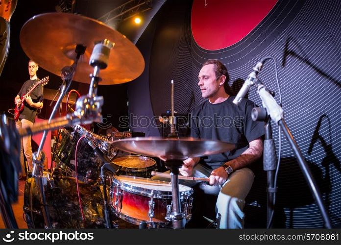 Musician playing drums on stage, rock music concert