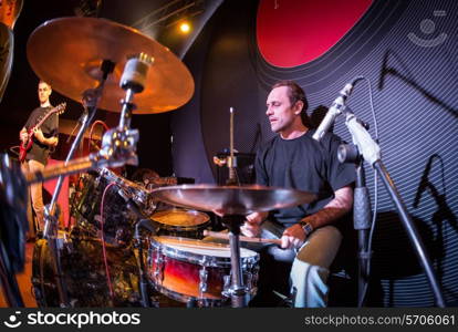 Musician playing drums on stage, rock music concert