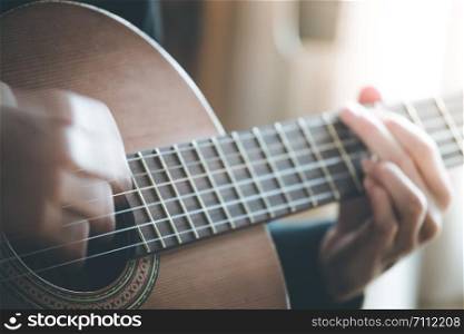 Musician plays a classical guitar, blurry hands, fretboard and fingers