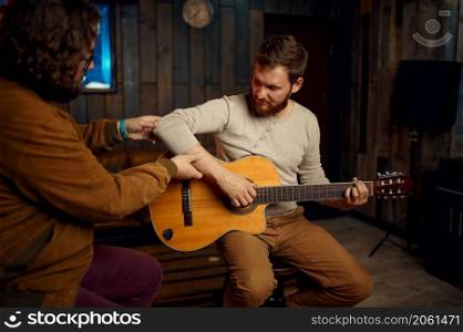 Musician showing right hand position to student. Guy improve his skills in playing guitar on lesson. Musician showing right hand position to student