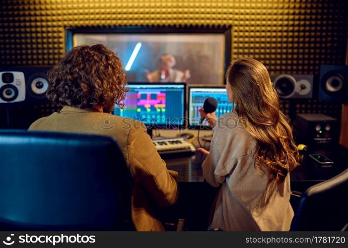 Musicians at mixing console, recording studio interior on background. Synthesizer and audio mixer, musician workplace, creative process, song record. Musicians at mixing console, recording studio