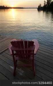 Muskoka chair on a dock at sunset in Lake of the Woods, Ontario