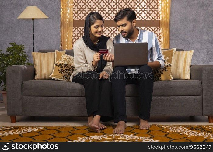 Muslim couple shopping online by using laptop and credit card