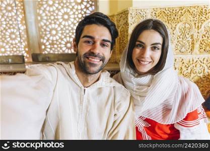 muslim couple taking selfie restaurant