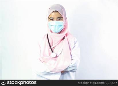Muslim female doctor with hijab wearing mask to protect virus and standing with confidence on white background. Medical and New Normal Concept.