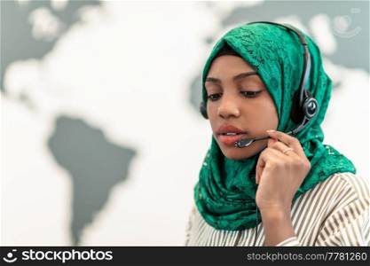  Muslim female with green hijab scarf customer representative businesswoman with phone headset helping and supporting online with the customer in a modern call center. High-quality photo.  Muslim female with green hijab scarf customer representative business woman with phone headset helping and supporting online with customer in modern call centre