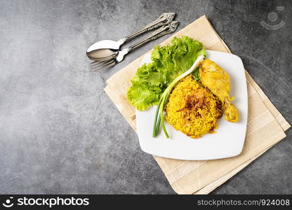 Muslim food biryani yellow rice with chicken in a white plate on floor